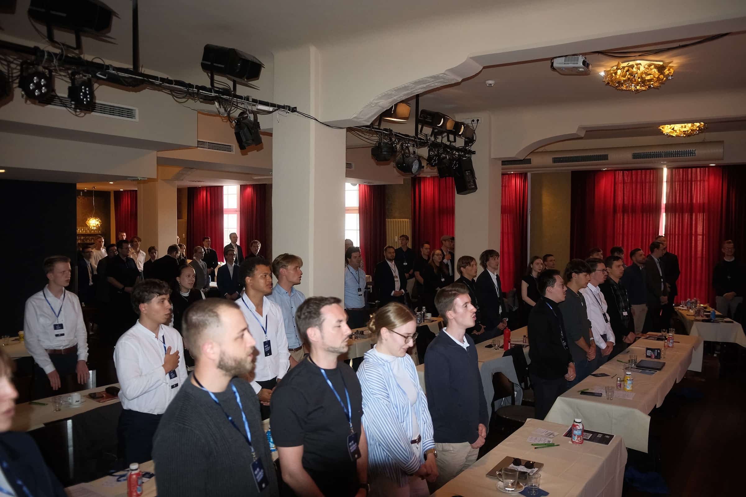 Die Delegierten stehen zwischen den Tischreihen im Saal
