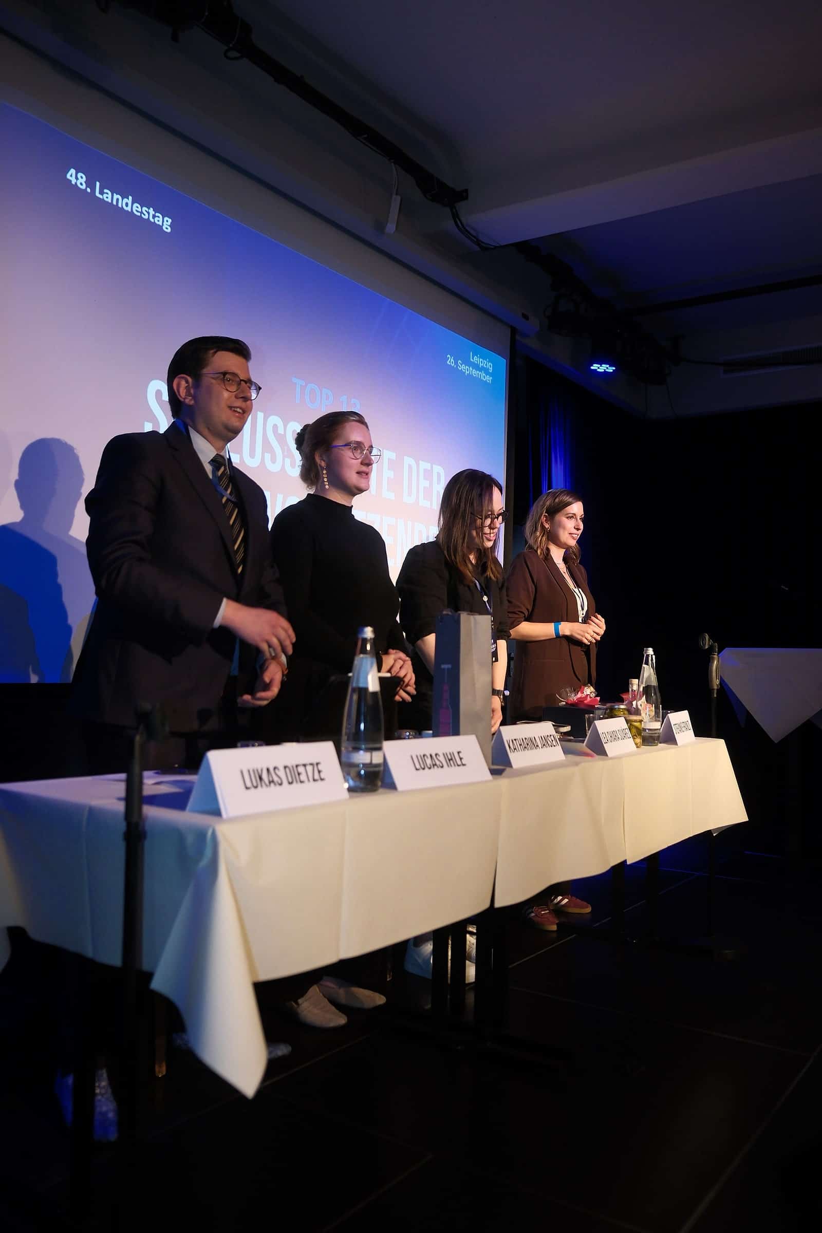 Vier Personen stehen zum Abschluss hinter dem Podiumstisch