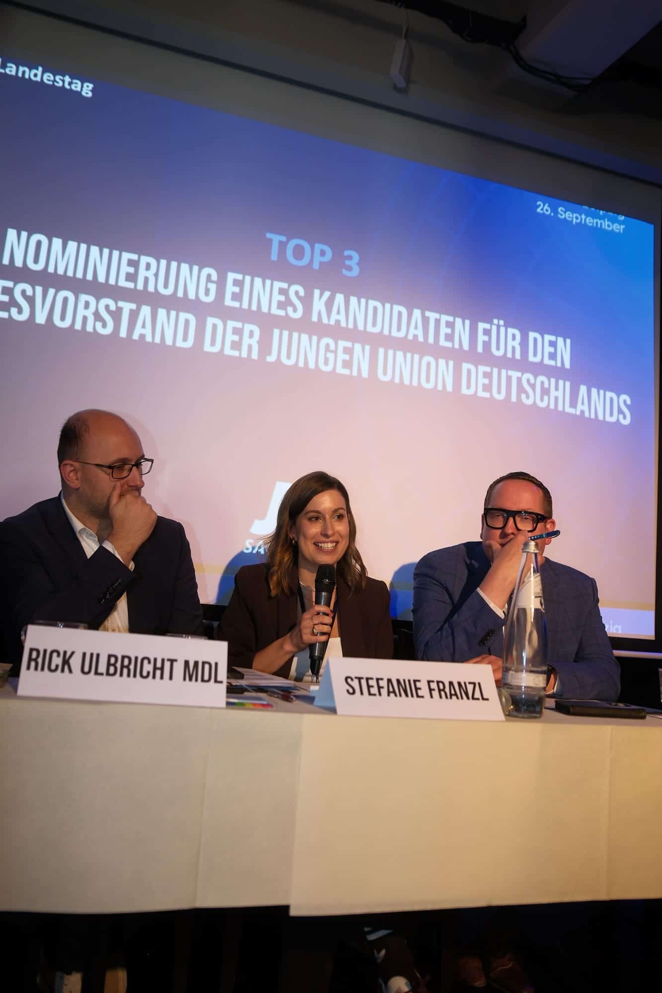Die Landesvorsitzende spricht am Podium, hinter ihr die Leinwand zur Nominierung für den Bundesvorstand