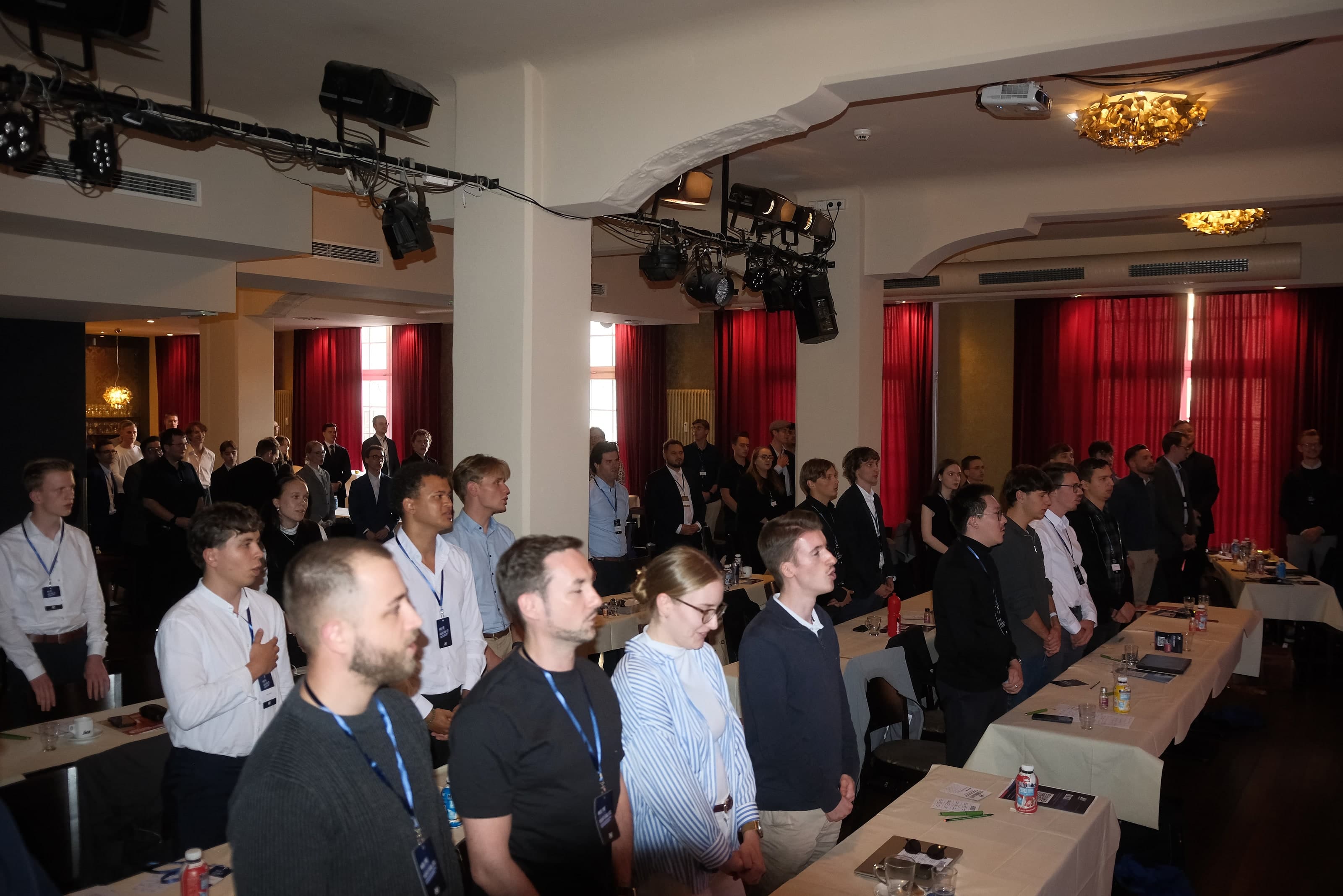 Delegierte stehen im Saal des Central Kabaretts, einige mit der Hand auf dem Herzen