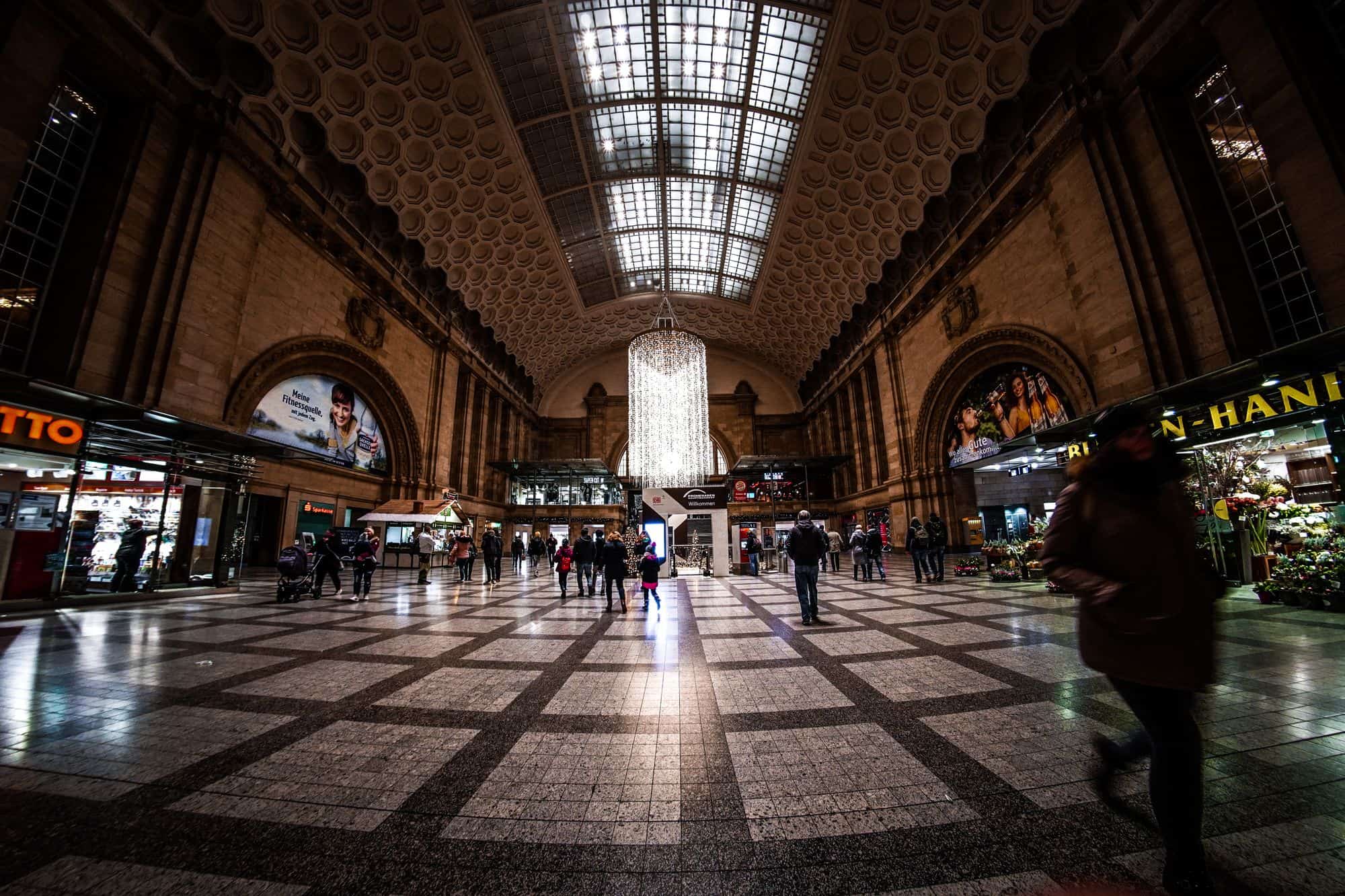 Die hell erleuchtete Haupthalle des Leipziger Hauptbahnhofs mit Reisenden
